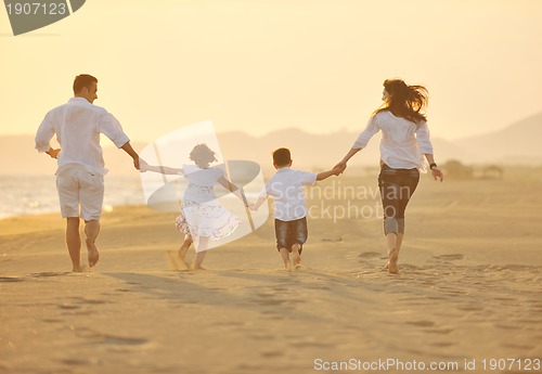 Image of happy young family have fun on beach at sunset