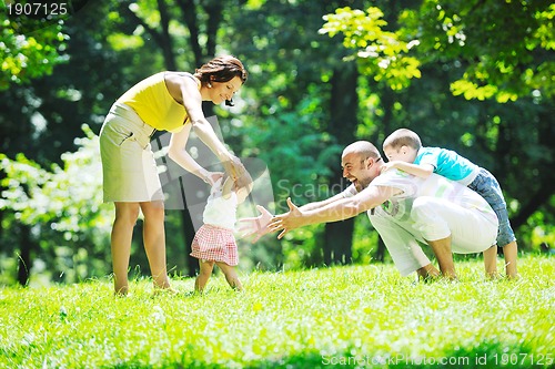 Image of happy young couple with their children have fun at park