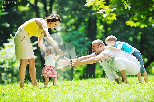 Image of happy young couple with their children have fun at park