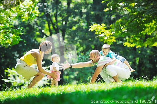 Image of happy young couple with their children have fun at park