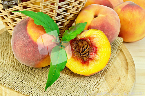 Image of Peaches with leaves and a basket on board