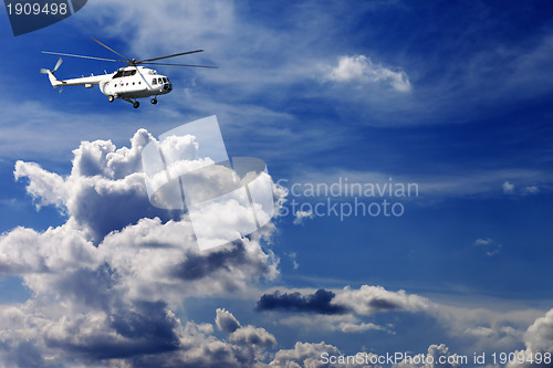 Image of Helicopter in blue sky with clouds