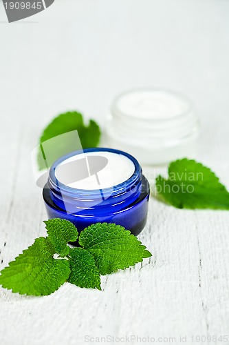 Image of face cream in jars with urtica leaves 