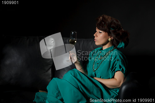 Image of Beautiful girl sitting on a sofa with glass of wine