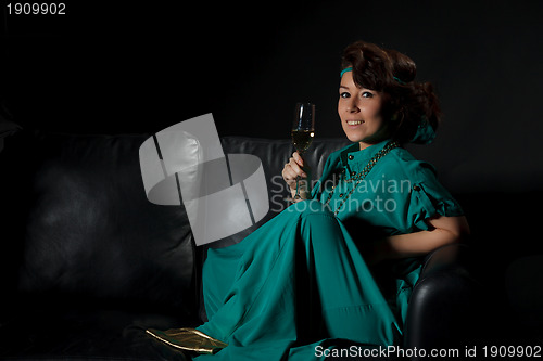 Image of Beautiful girl sitting on a sofa with glass of wine