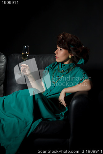 Image of Beautiful girl sitting on a sofa with glass of wine