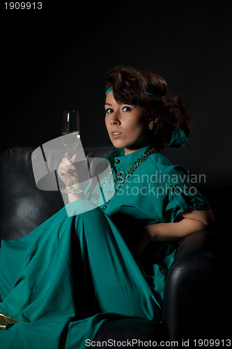 Image of Beautiful girl sitting on a sofa with glass of wine