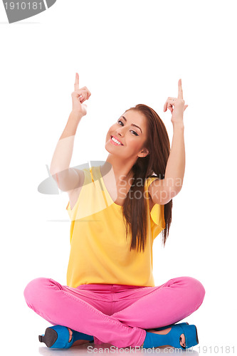 Image of seated young casual woman pointing up