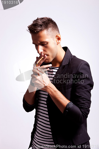 Image of young fashion guy lighting his cigarette 