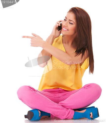 Image of seated casual woman talking on phone and pointing