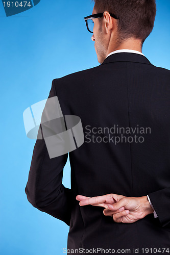 Image of business man with fingers crossed behind back