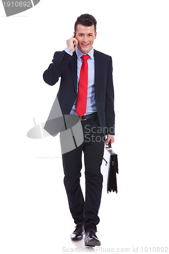 Image of Business man with suitcase walking and talking on phone