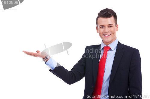 Image of  young man in a suit presenting or holding something 
