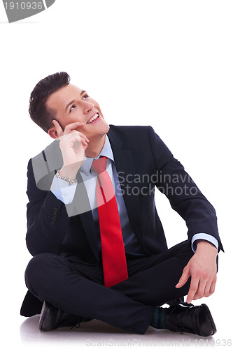 Image of young seated business man looking up 