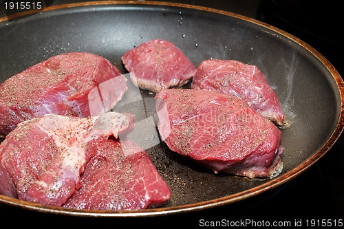 Image of beef meat on pan with pepper and sea salt