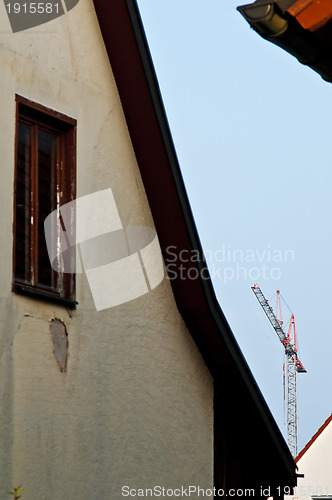 Image of building crane with old house