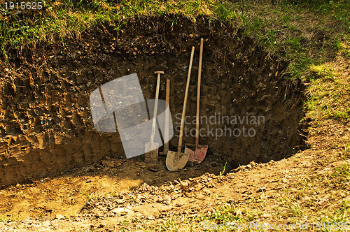 Image of hole with shovel,spade and hoe