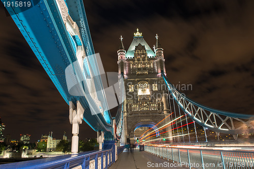 Image of Detail of Tower Bridge in London at night with car light trail -