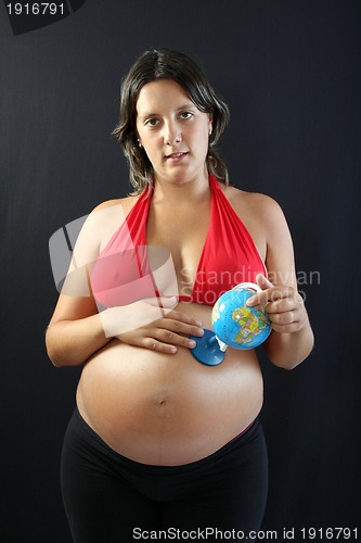 Image of beautiful Pregnant woman with beautiful belly holding a world gl