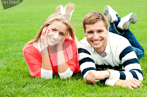 Image of Charming young couple lying on green grass