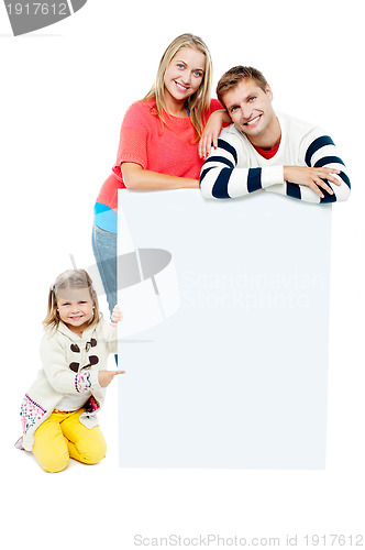 Image of Portrait of happy family presenting blank whiteboard