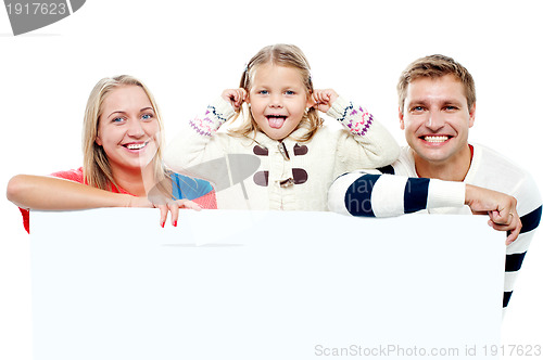 Image of Young beautiful family behind white blank ad board