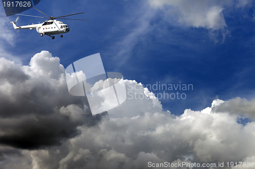 Image of Helicopter in blue sky with clouds