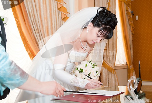 Image of Pretty bride signing document