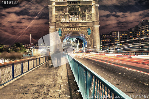 Image of Tower Bridge in London, UK at night with traffic and moving red 