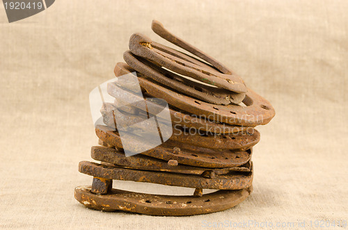 Image of stack of old retro horse shoes on linen background 