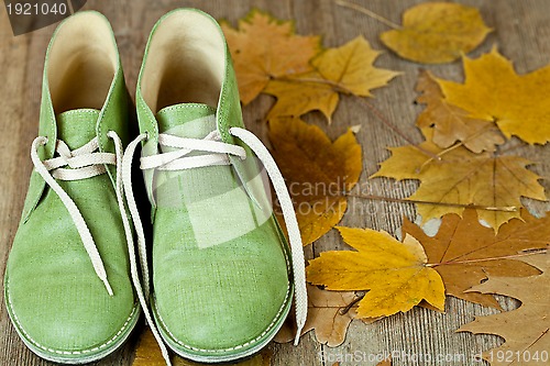 Image of pair of green leather boots and yellow leaves
