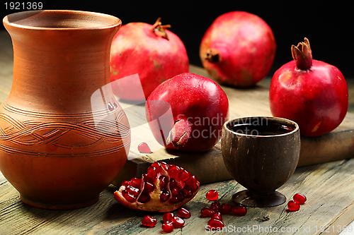 Image of Fresh juice in cup and ripe pomegranates.
