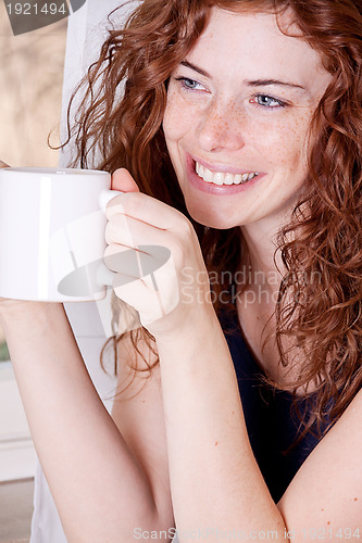 Image of pretty young redhead woman with freckles and coffe