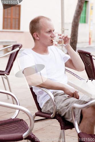 Image of young man sitting outdoor in a cafe in summer
