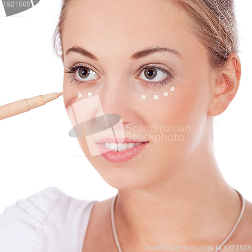 Image of beautiful woman applying make up on face