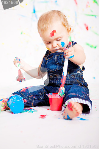 Image of cute little baby painting and splatter with colours