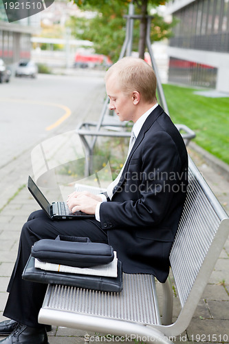 Image of business man sitting outdoor working with notebook