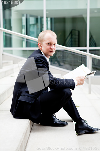 Image of young business man is reading newspaper outdoor