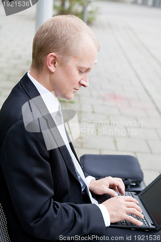 Image of business man sitting outdoor working with notebook