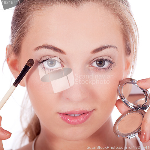 Image of beautiful woman applying make up on face