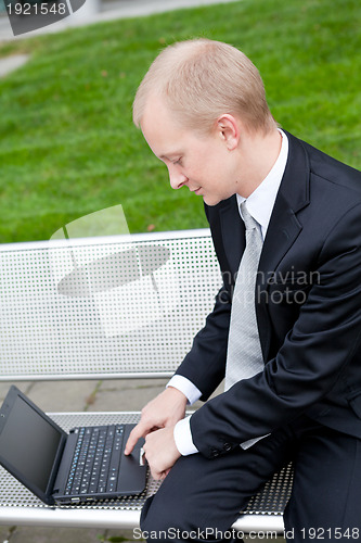 Image of business man sitting outdoor working with notebook