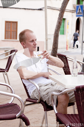 Image of young man sitting outdoor in a cafe in summer