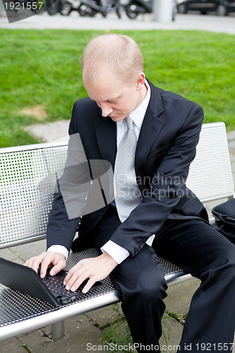 Image of business man sitting outdoor working with notebook