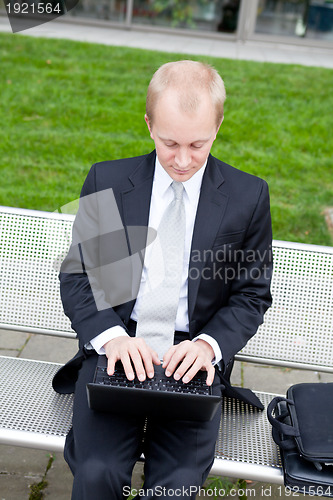 Image of business man sitting outdoor working with notebook