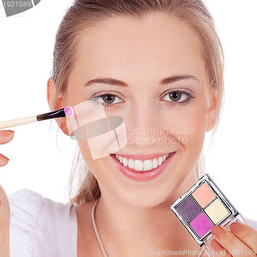 Image of beautiful woman applying make up on face