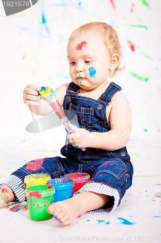 Image of cute little baby painting and splatter with colours