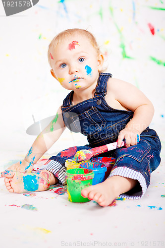 Image of cute little baby painting and splatter with colours