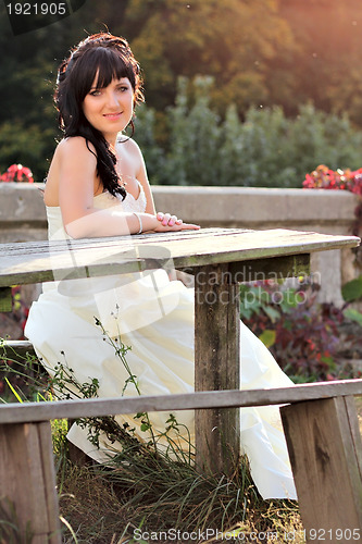 Image of Girl in the wedding dress sitting on the bench