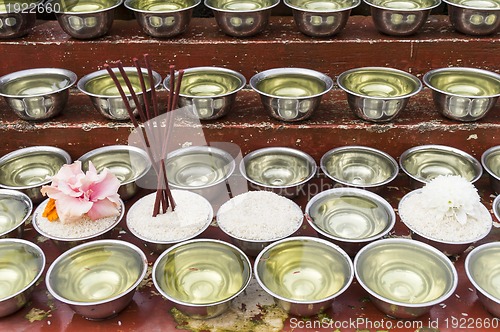 Image of small bowls with water and rice around a temple