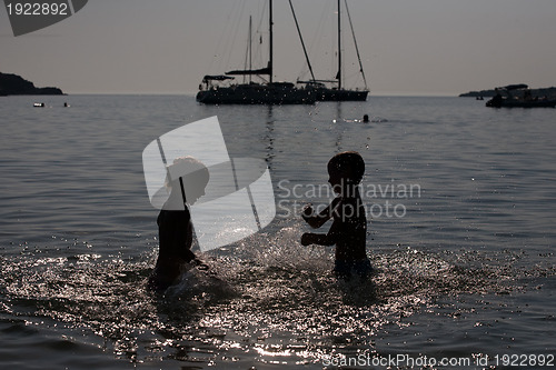 Image of silhouettes of children playing in sea water
